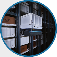 A robotic system stacking white storage bins on tall warehouse shelves. The scene conveys efficiency and modern automation in a cool, industrial environment.