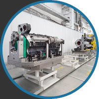 Industrial machines in a clean, white factory setting. The machinery is metallic with green accents, positioned on sturdy platforms, conveying precision and technology.